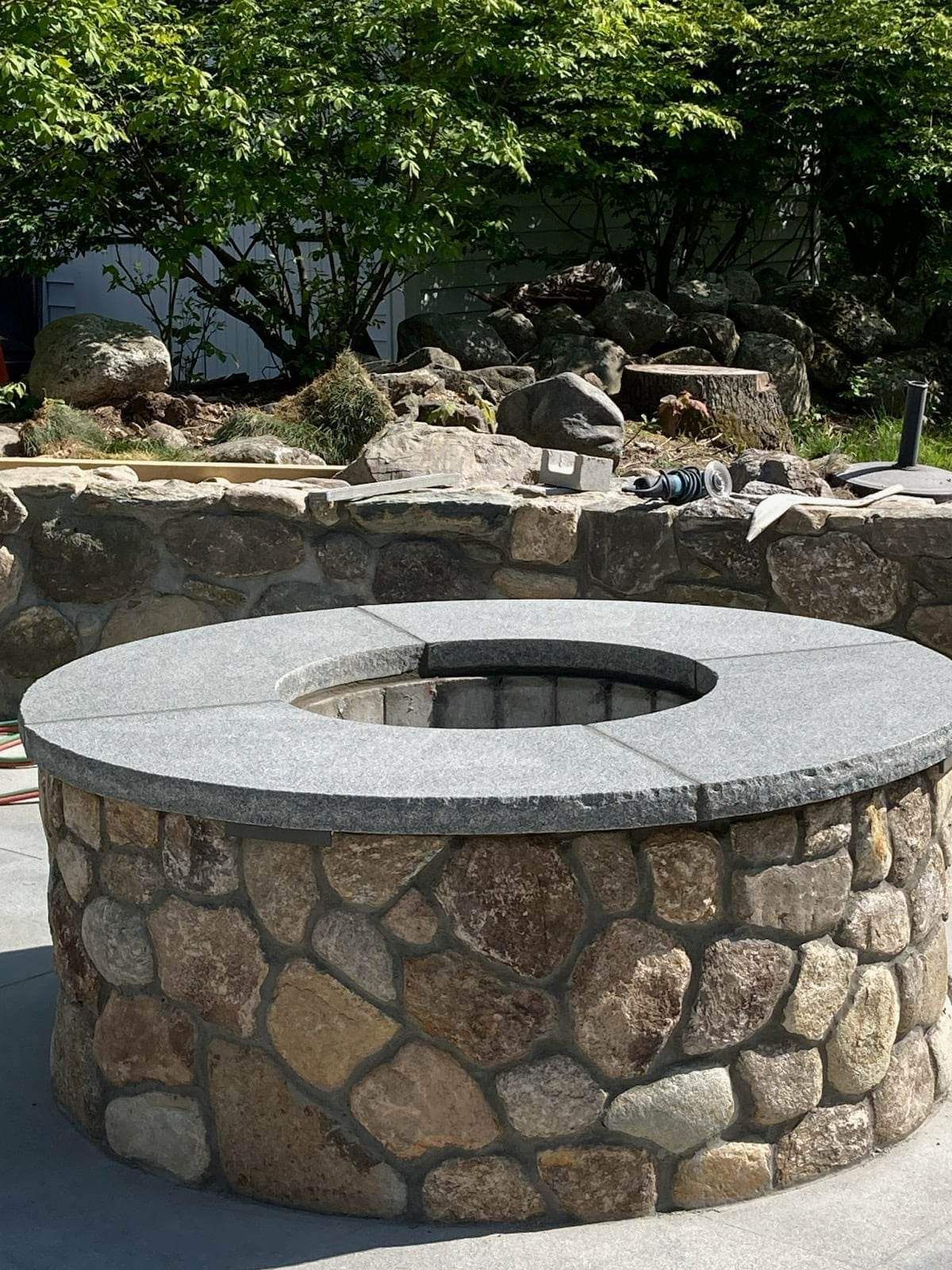 Stone fire pit with a circular opening in a landscaped garden setting