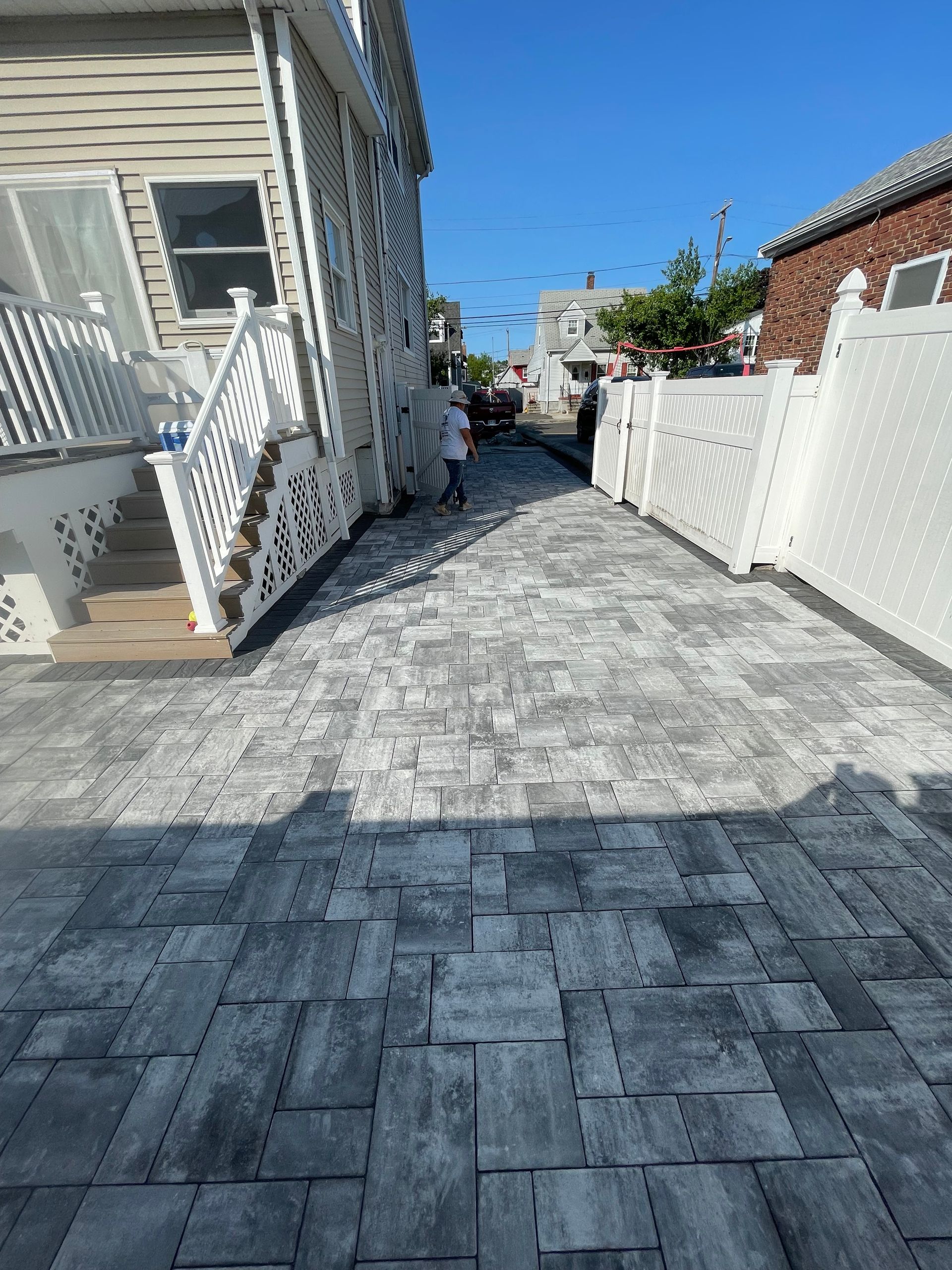 Narrow paved alley between white houses under a bright blue sky