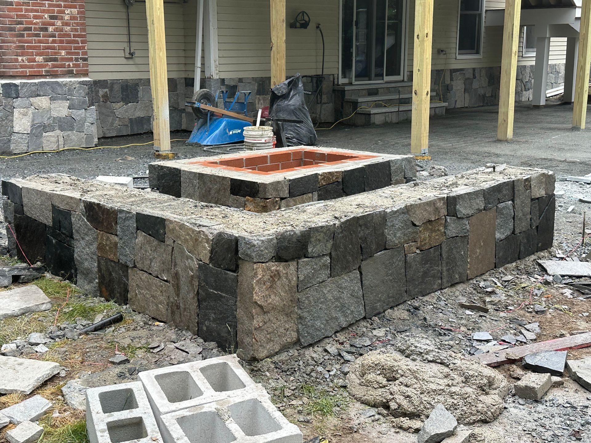 Stone retaining wall around a raised concrete planter on a porch, with construction debris nearby.