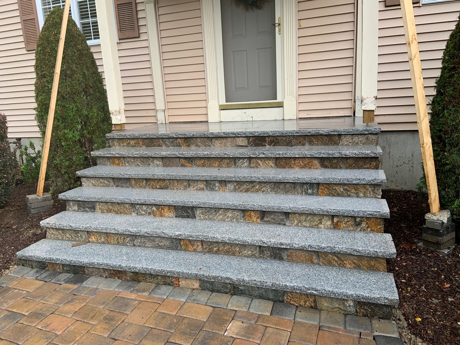 Stone front steps with potted evergreens leading to a house entrance