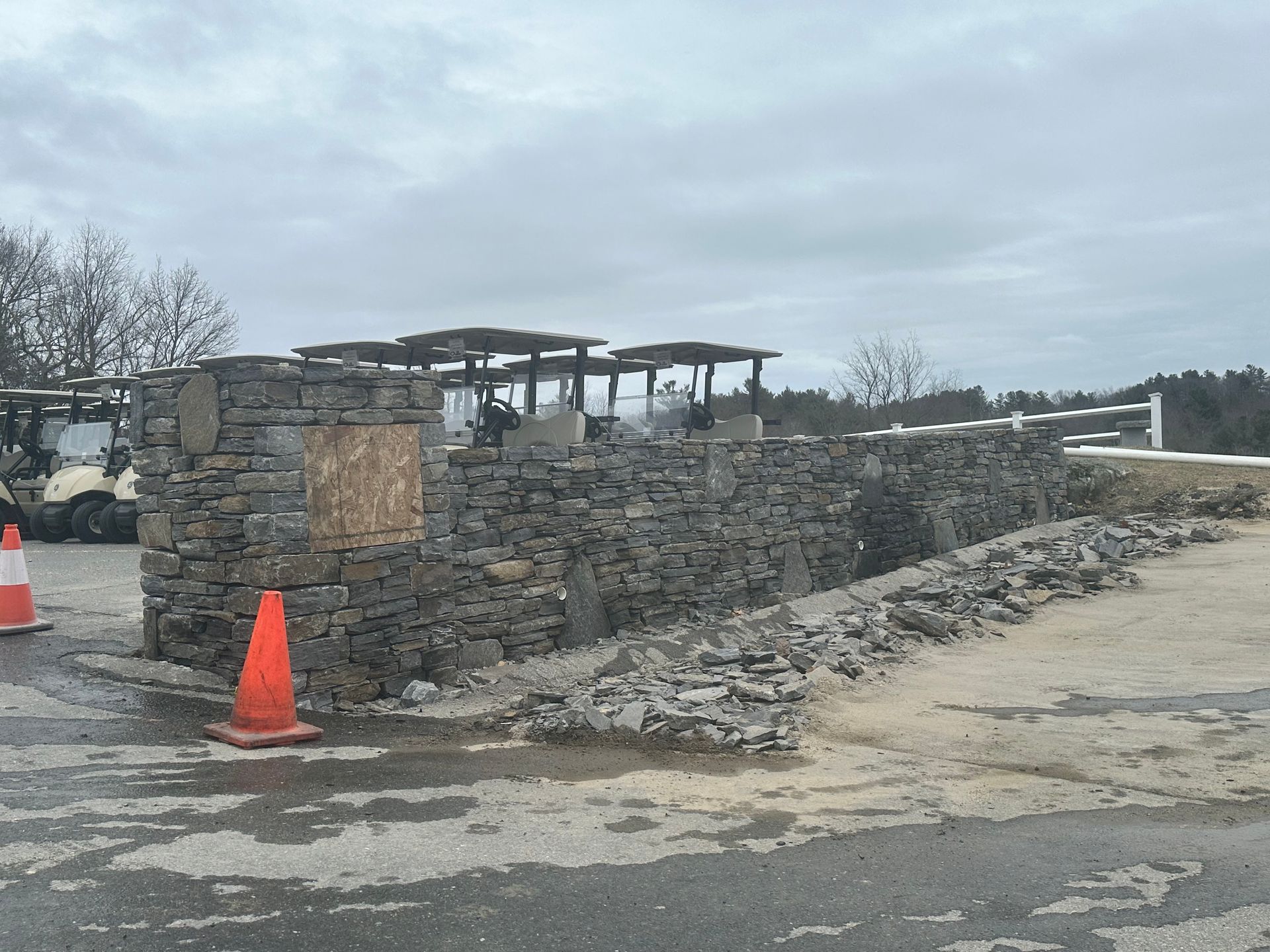 Stone ruin beside a road with orange traffic cones under a cloudy sky