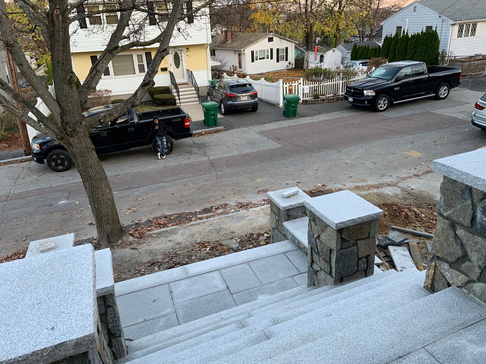 Snow-covered front steps overlooking a quiet residential street with parked cars and houses.