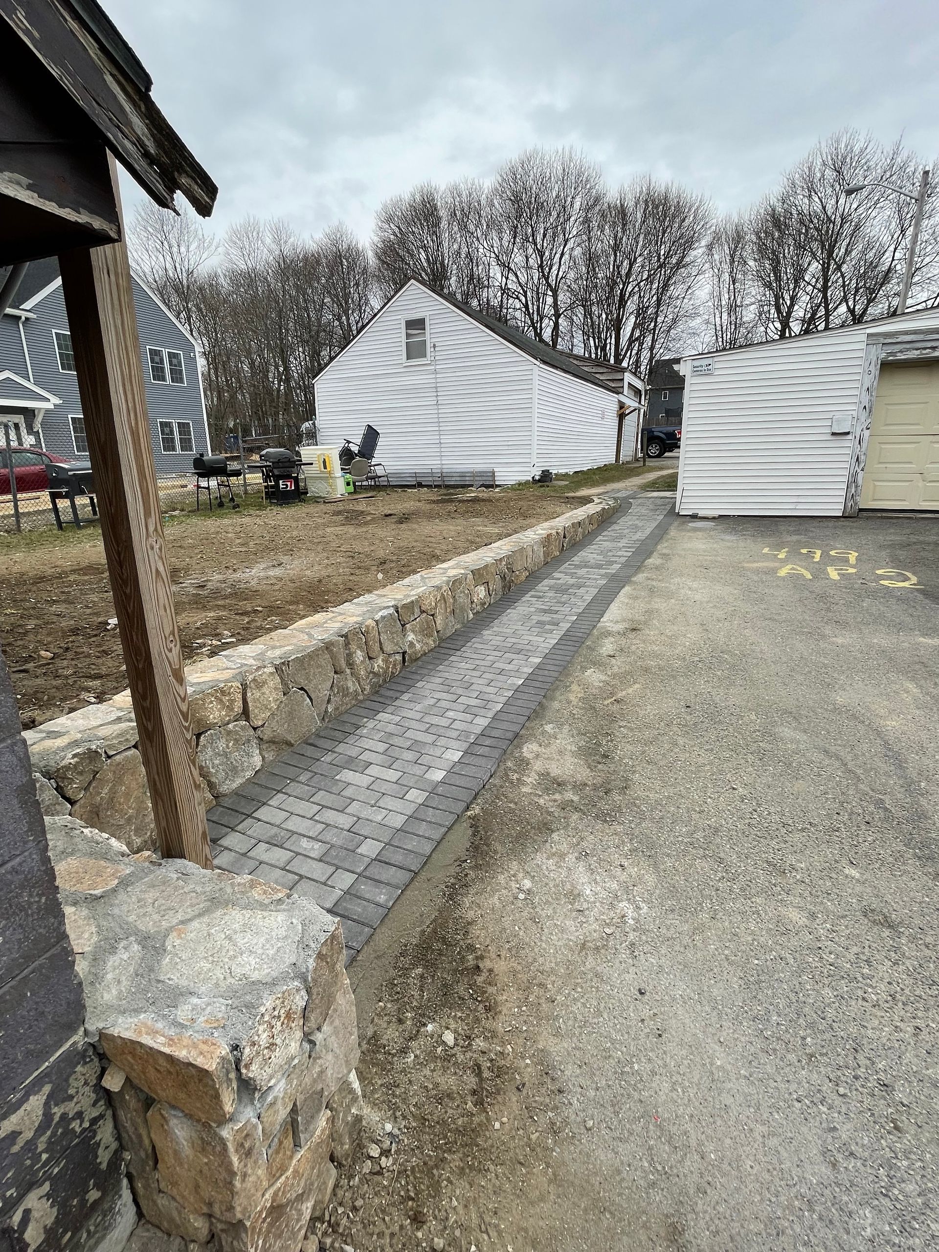 Gravel path beside white tents and a stone-lined drainage channel in a rural outdoor area