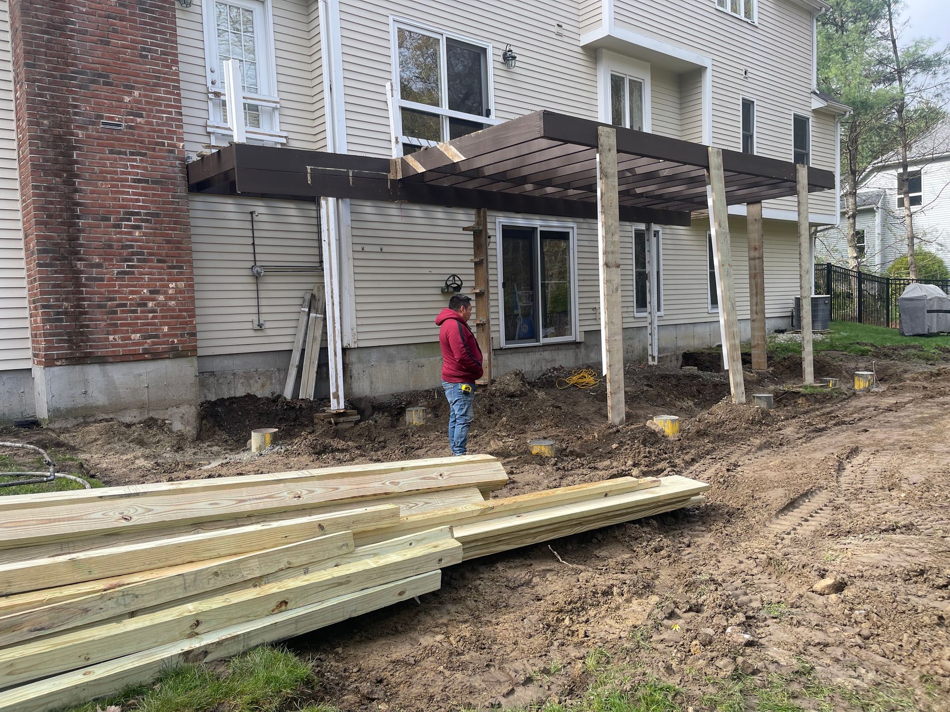 Backyard construction site with a deck under renovation and lumber stacked in the foreground