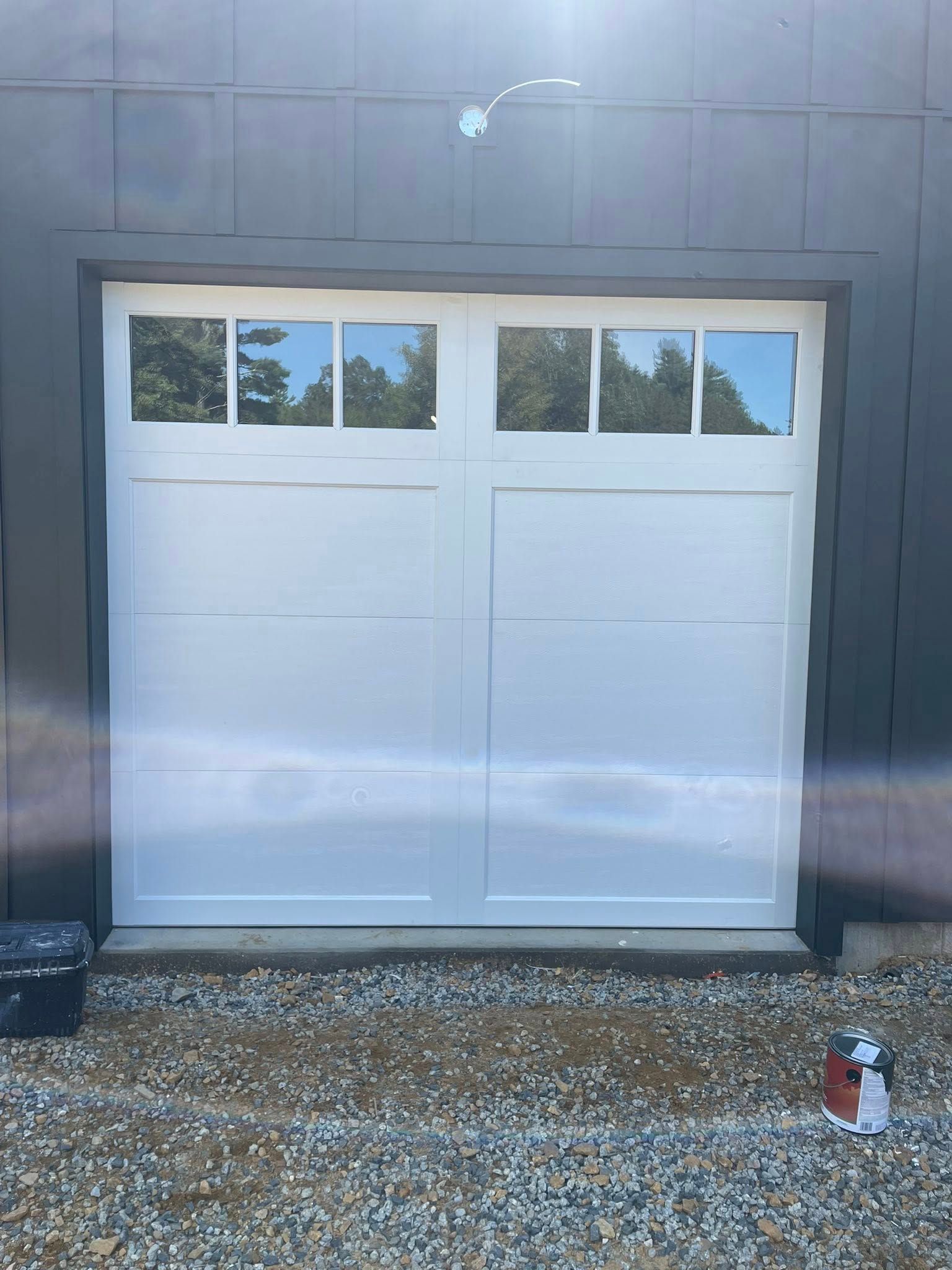 White garage door with six glass window panes, gravel ground.