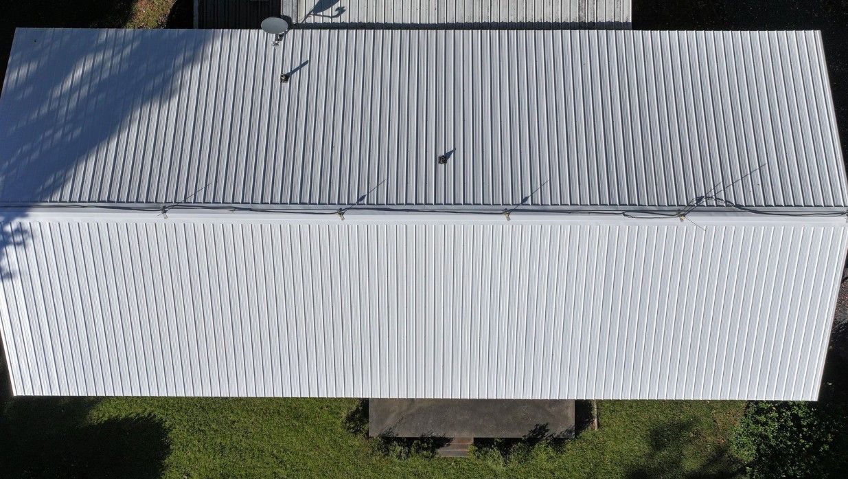 Overhead view of a white metal roof on a rectangular building with a ridge line in the center.
