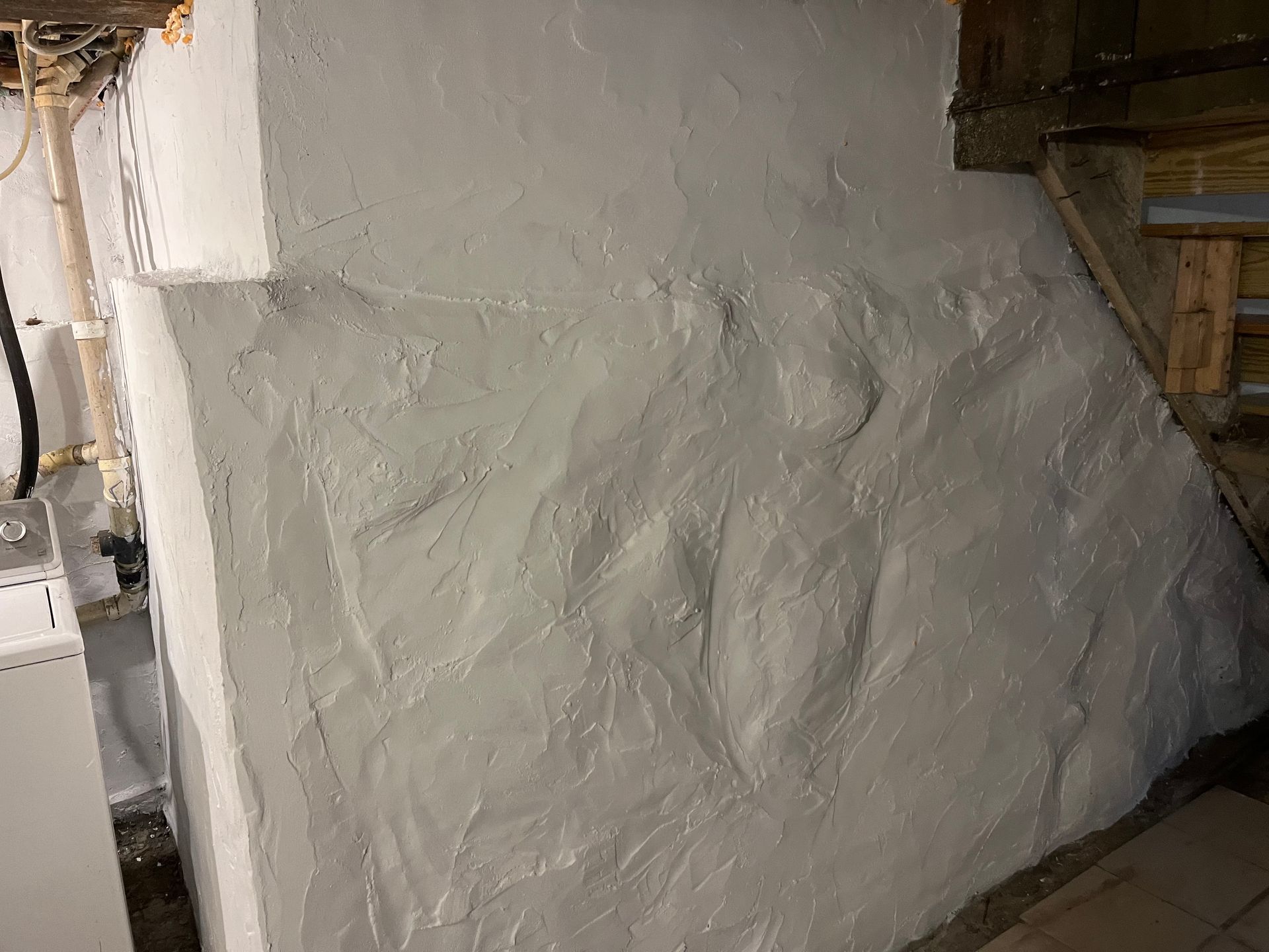 A white wall in a basement with a staircase in the background