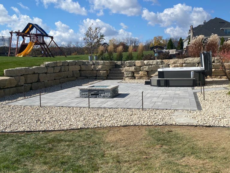 A backyard with a fire pit and a playground in the background