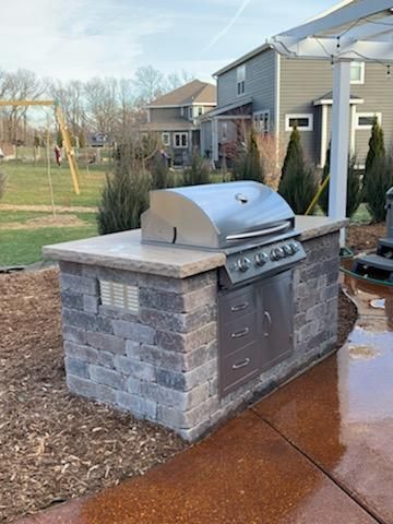 A stainless steel grill is sitting on top of a brick counter.