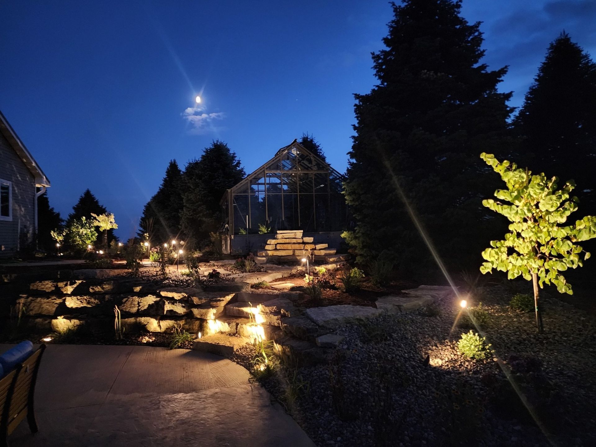 A house is lit up at night with a full moon in the sky