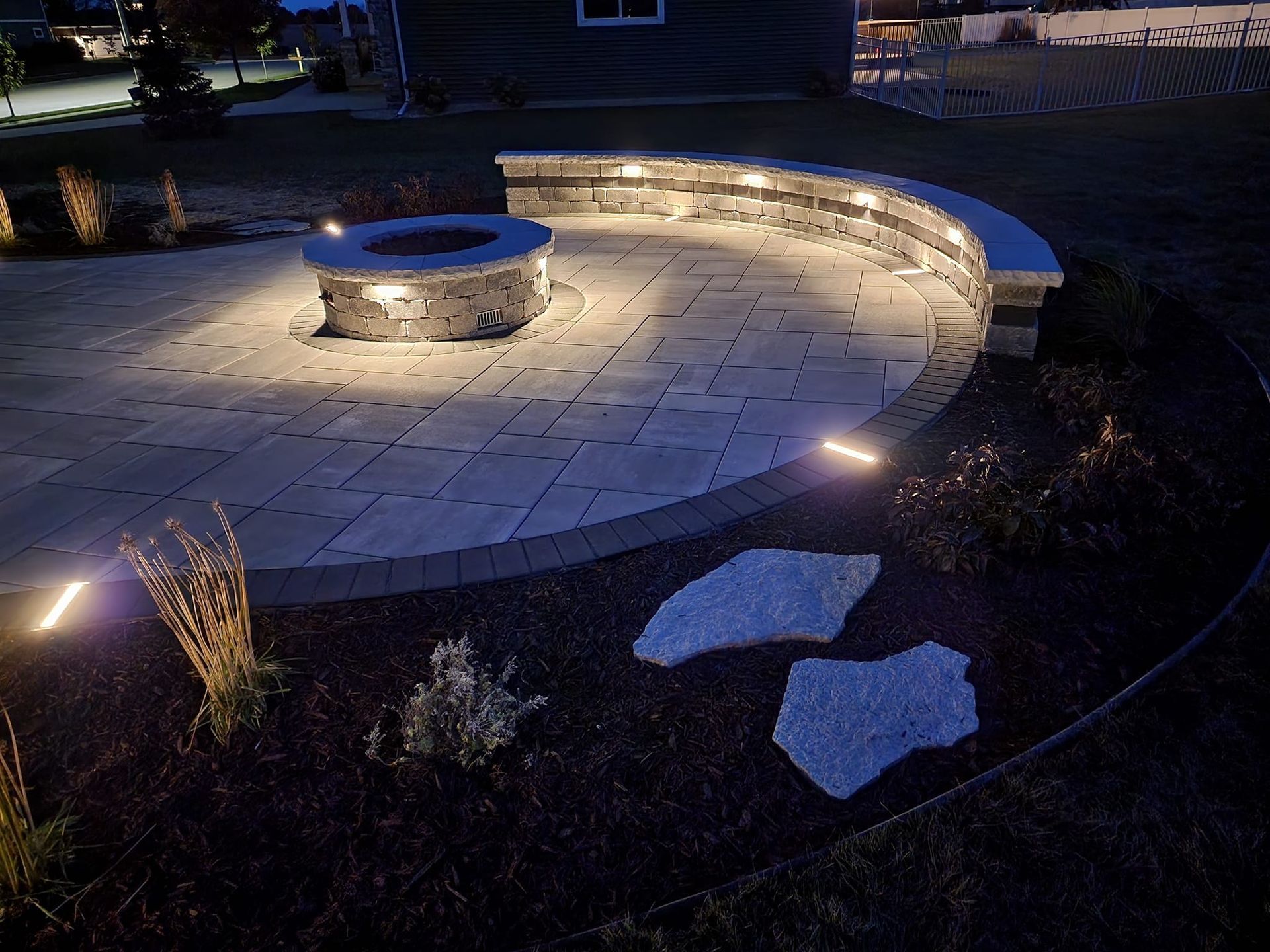 A fire pit is lit up at night on a patio.