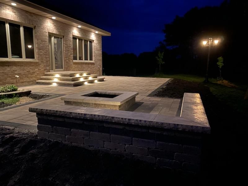 A brick house with a fire pit in front of it at night.