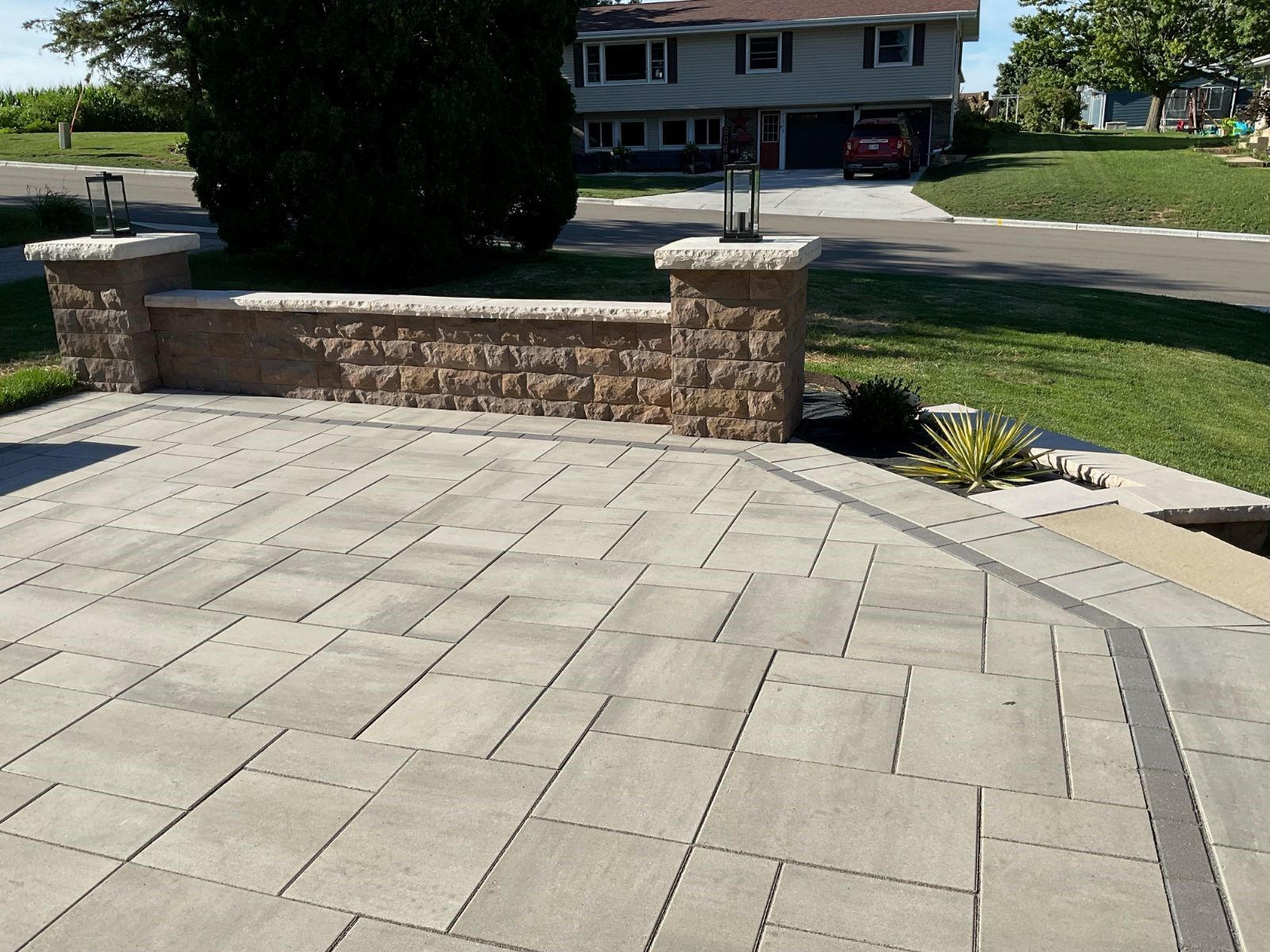 A driveway in front of a house with a brick wall