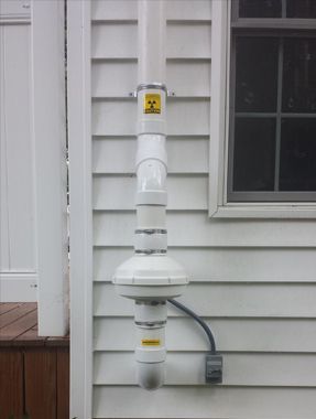 A white pipe is attached to the side of a house