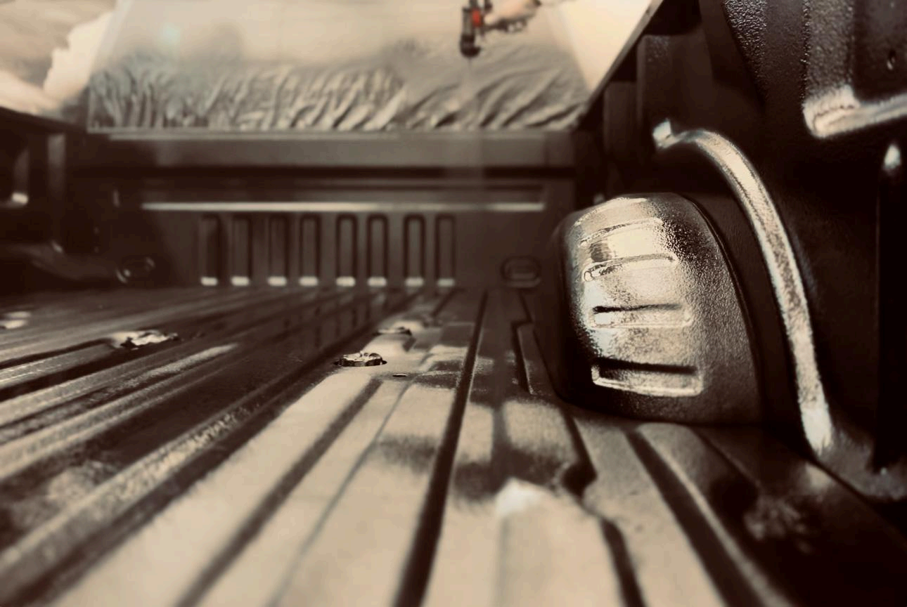 A close-up, sepia-toned view looking down into the corrugated metal bed of a pickup truck.
