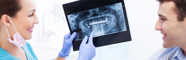 Dentist holding and pointing in xray of patient