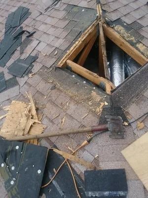 Damaged roof with exposed beams and missing shingles; a hammer rests on the structure.