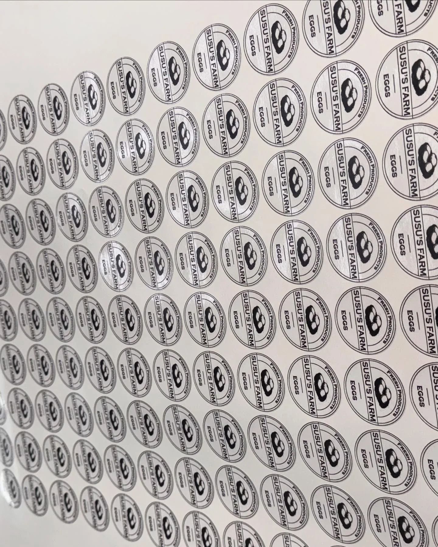 Sheet of clear stickers with repeating black circular logo.