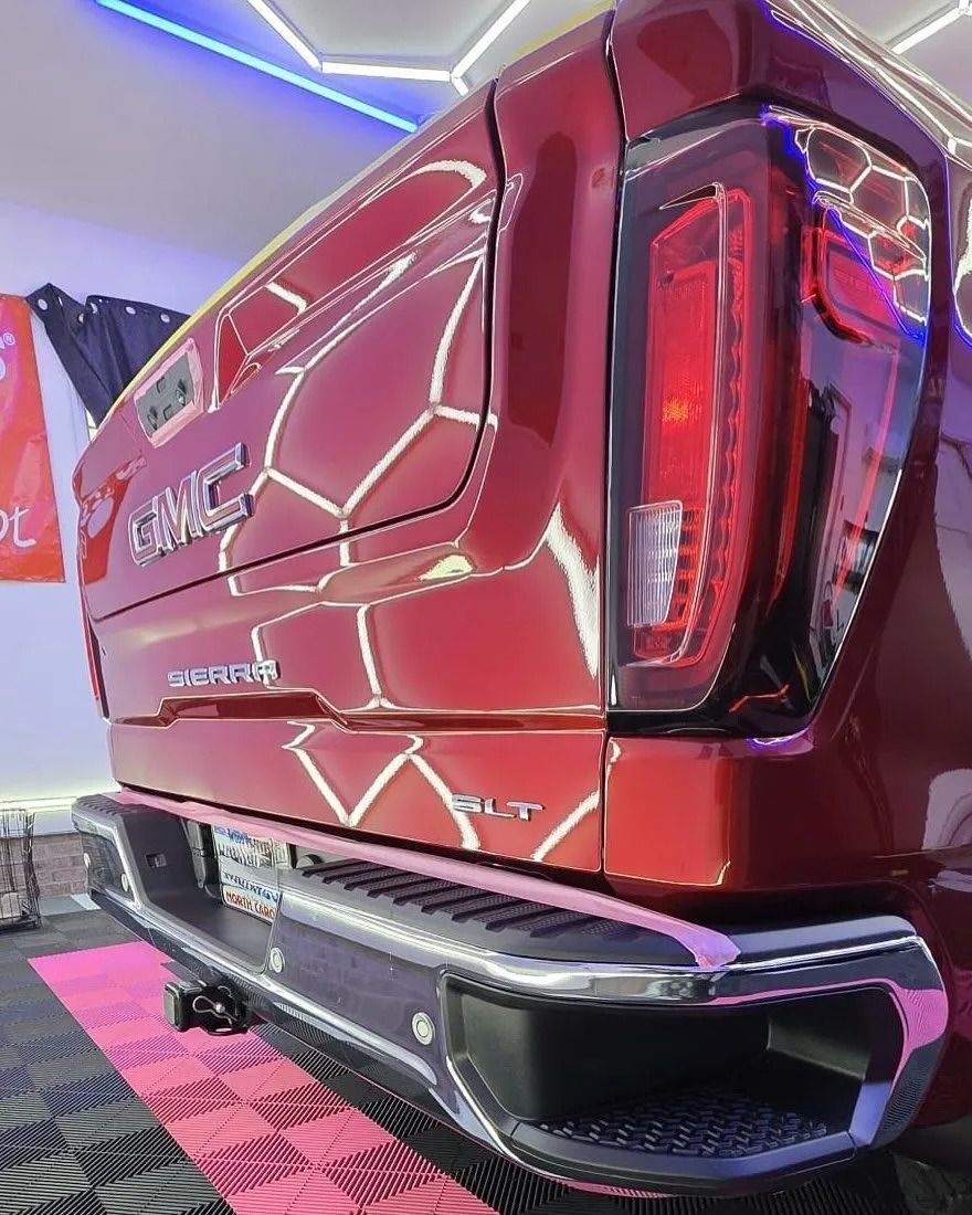 Red GMC truck's rear view, showing taillight, bumper, and tailgate.