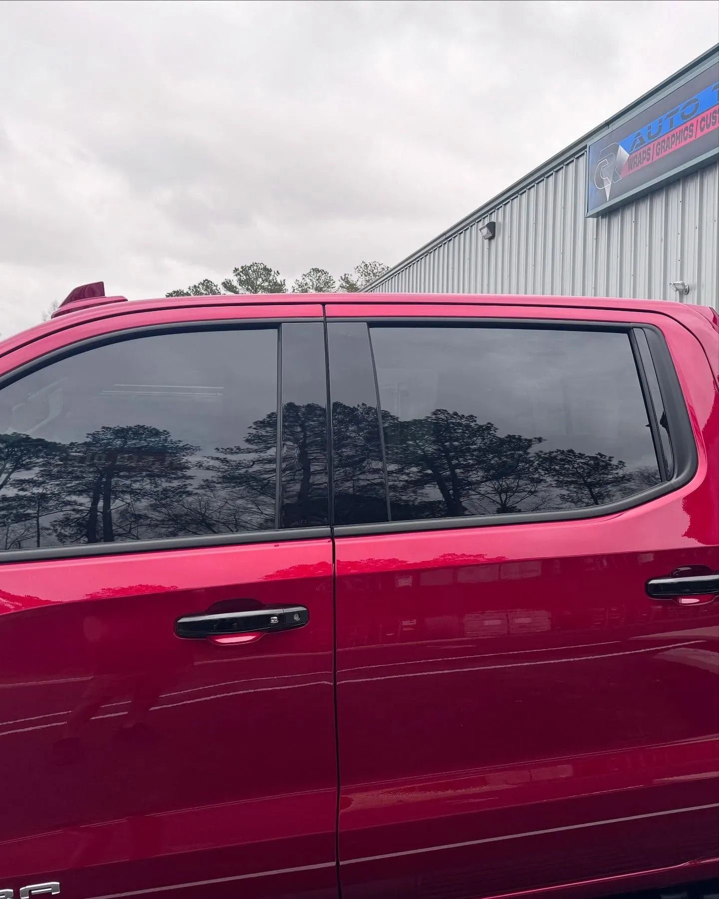 Red truck with tinted windows parked outside a building.