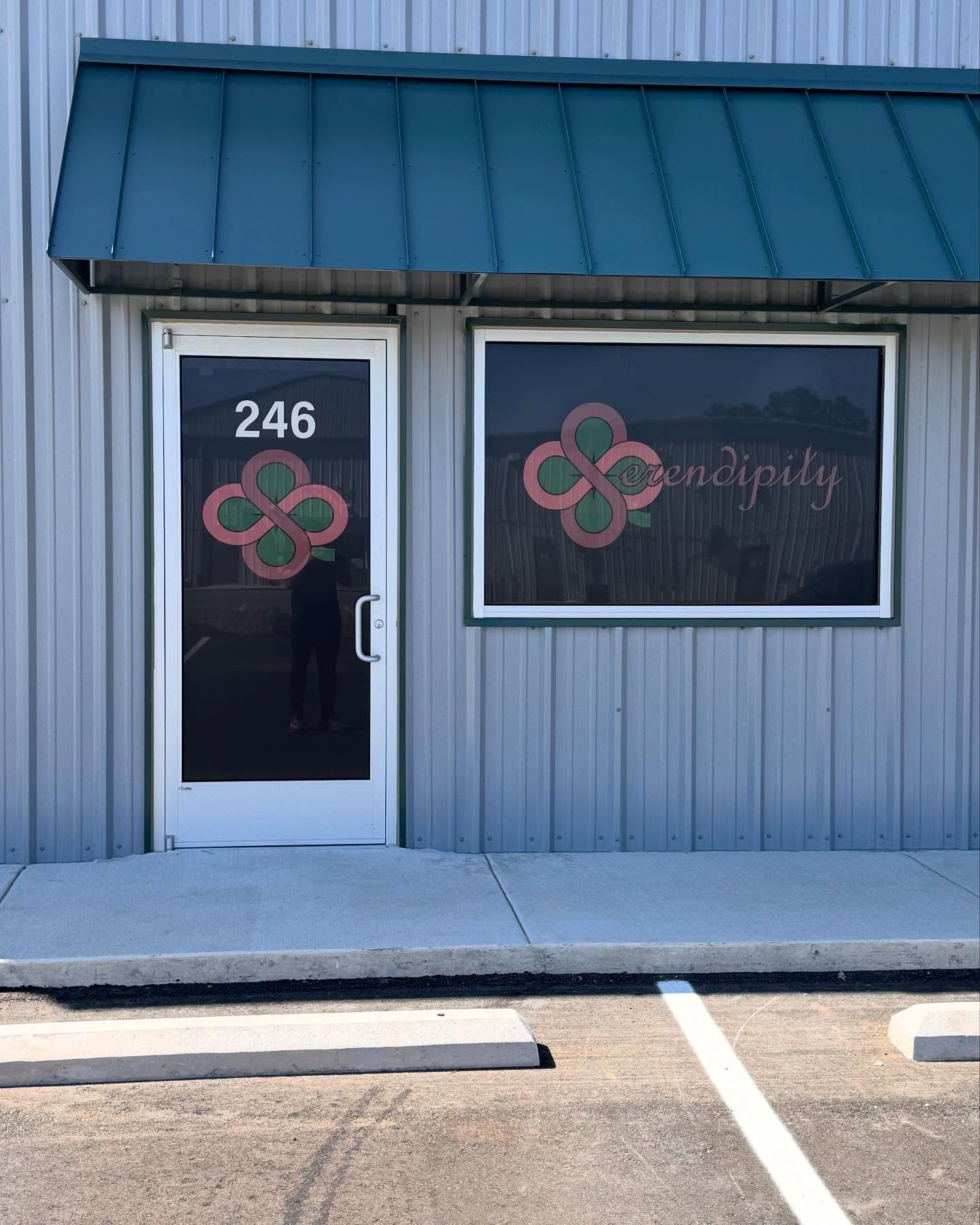 Exterior of a business storefront with number 246, a green awning, a window, and a door. 