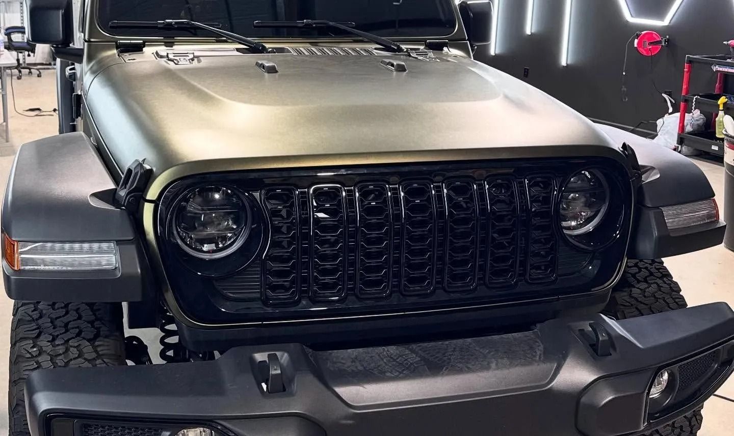 Green Jeep Wrangler with black grill and fender flares.