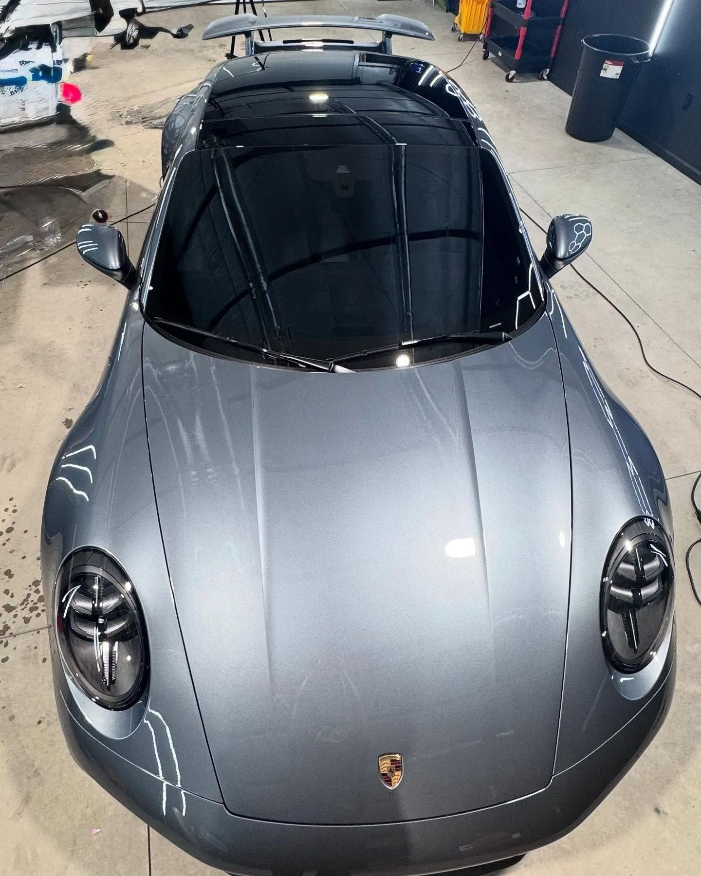 Gray Porsche sports car with tinted windows, parked indoors.