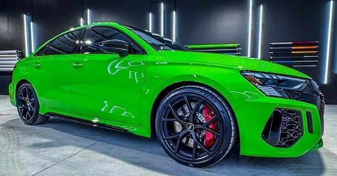 Bright green Audi RS3, black wheels, red brake calipers, in a shop.