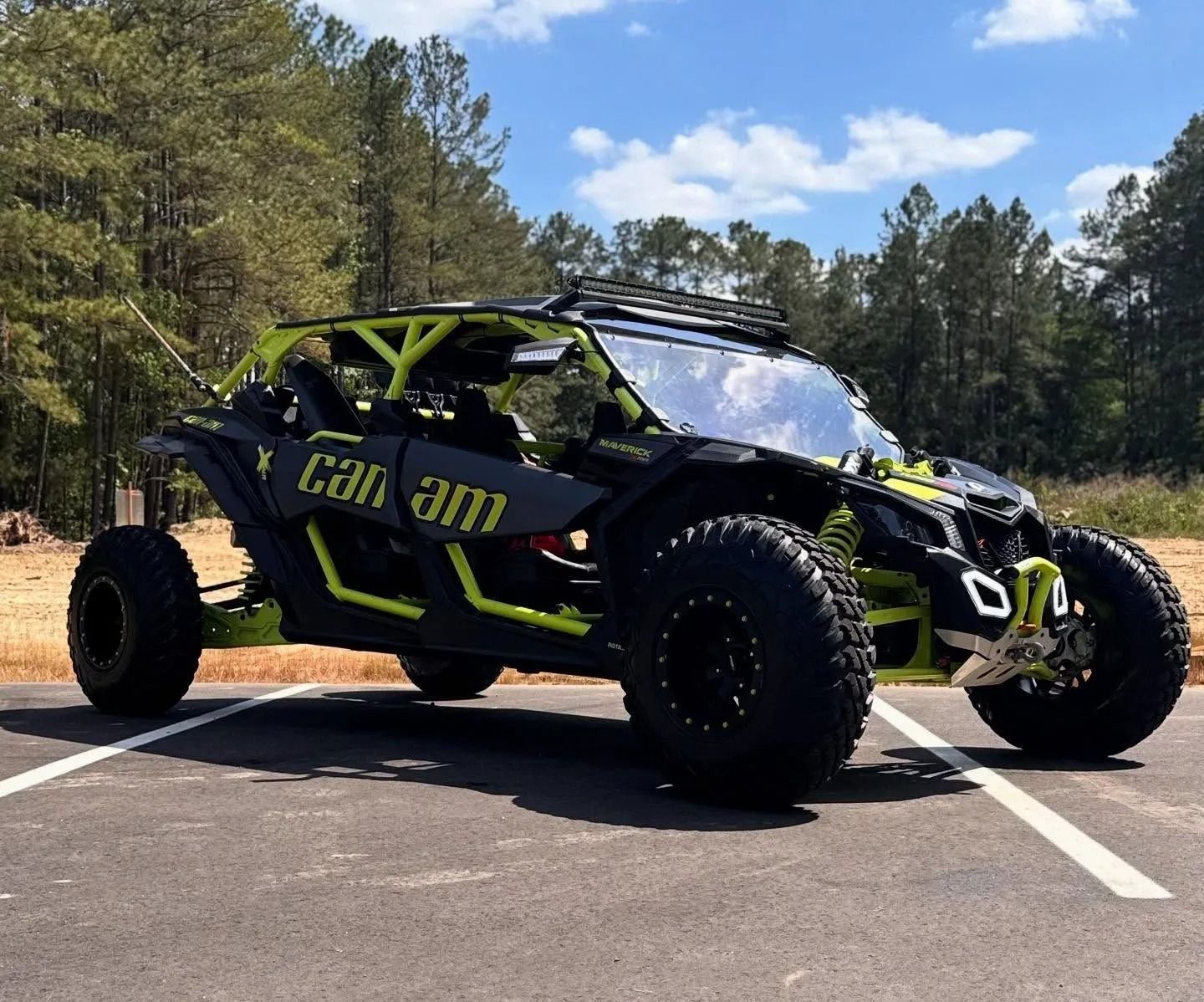 Black and lime green Can-Am Maverick side-by-side vehicle parked outdoors on a sunny day.
