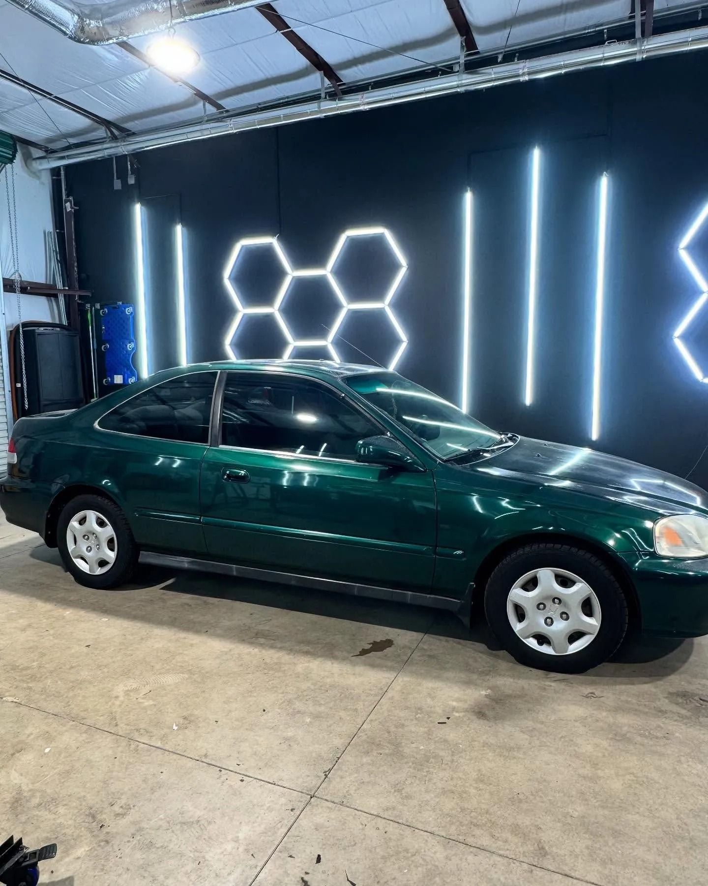 Green Honda Civic coupe in a garage with neon lights.