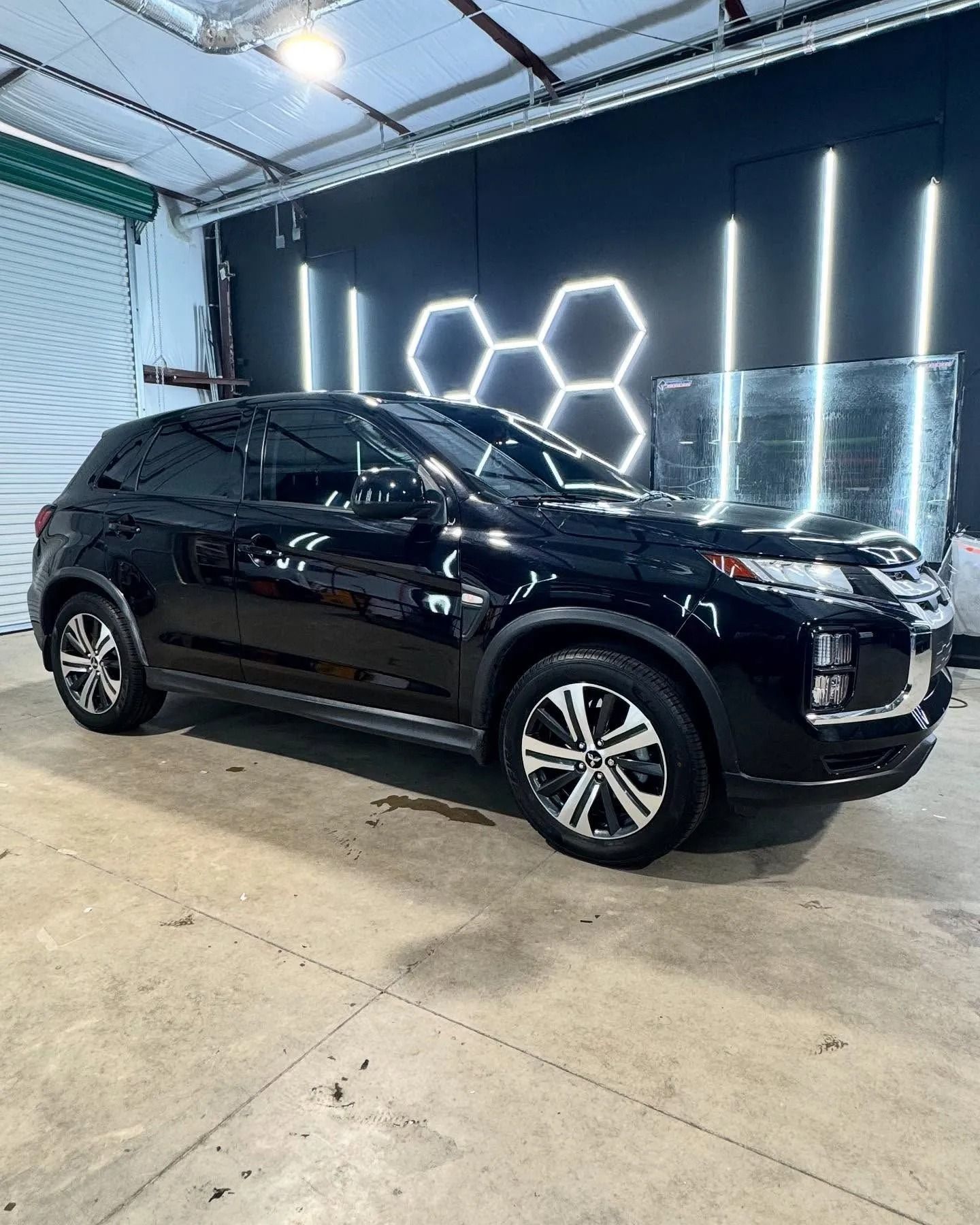 Black SUV in a well-lit garage with honeycomb-shaped lights in the background.