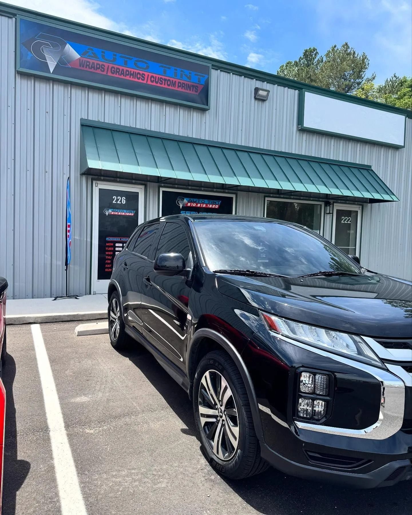 Black SUV parked in front of a storefront with signage.