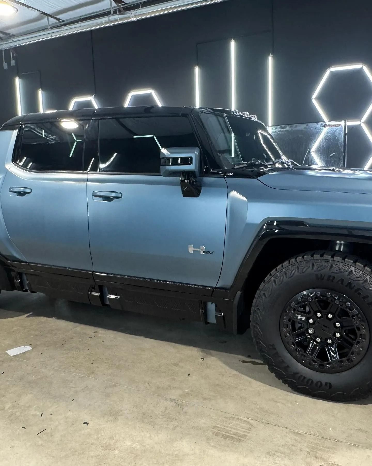 Blue and black Hummer EV truck in a garage.