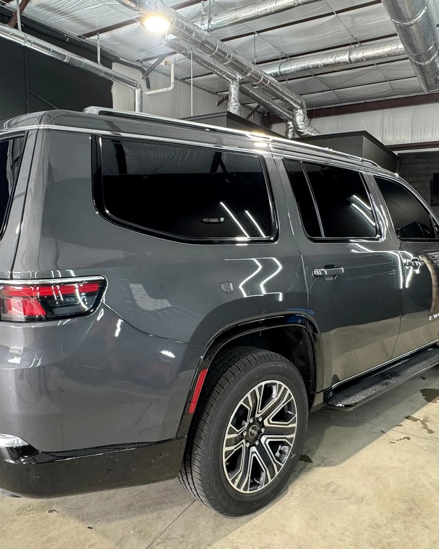 Gray SUV with black tinted windows, parked indoors. Chrome wheels and trim visible.