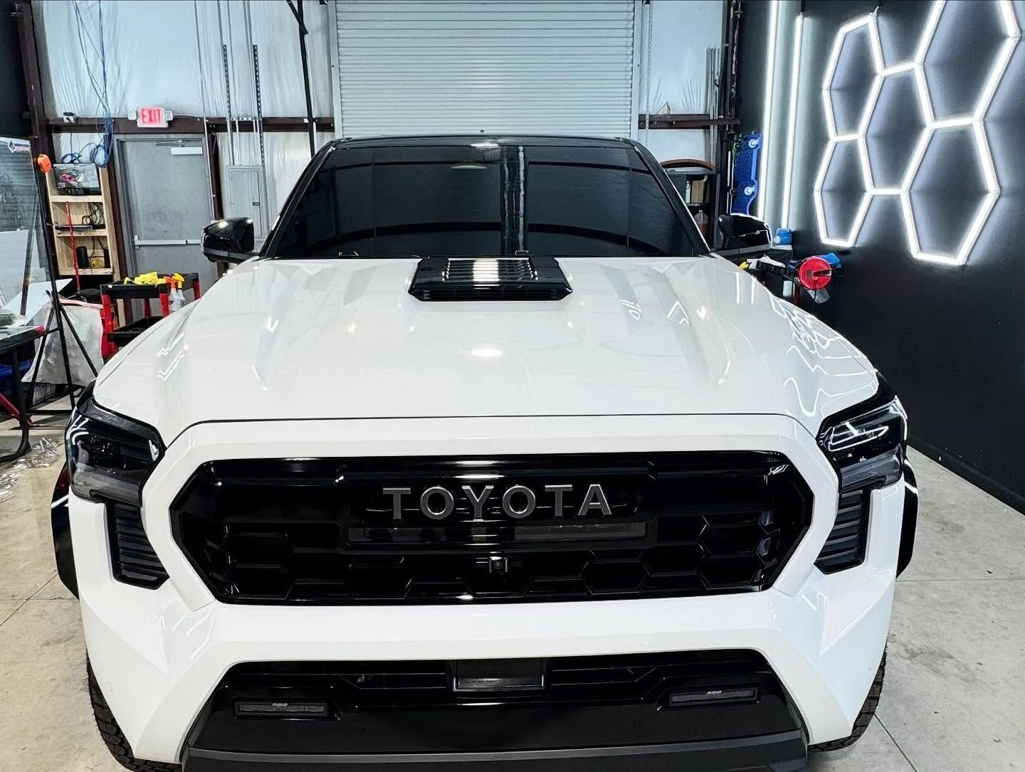 White Toyota truck with black accents, parked in a garage.
