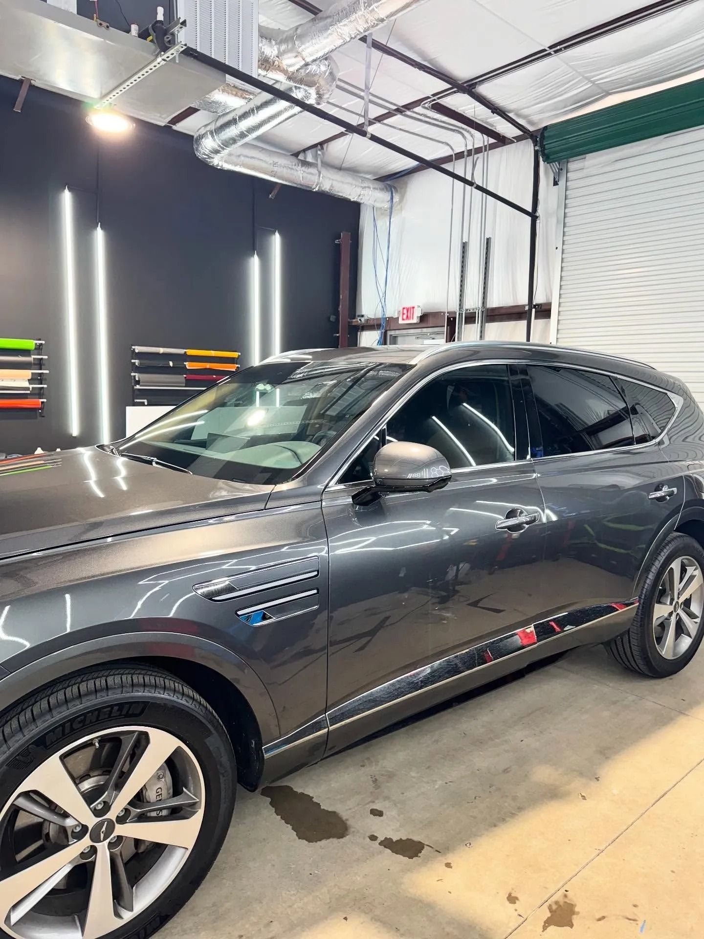 Gray SUV inside a shop with tinted windows, red and blue accents, bright lights.