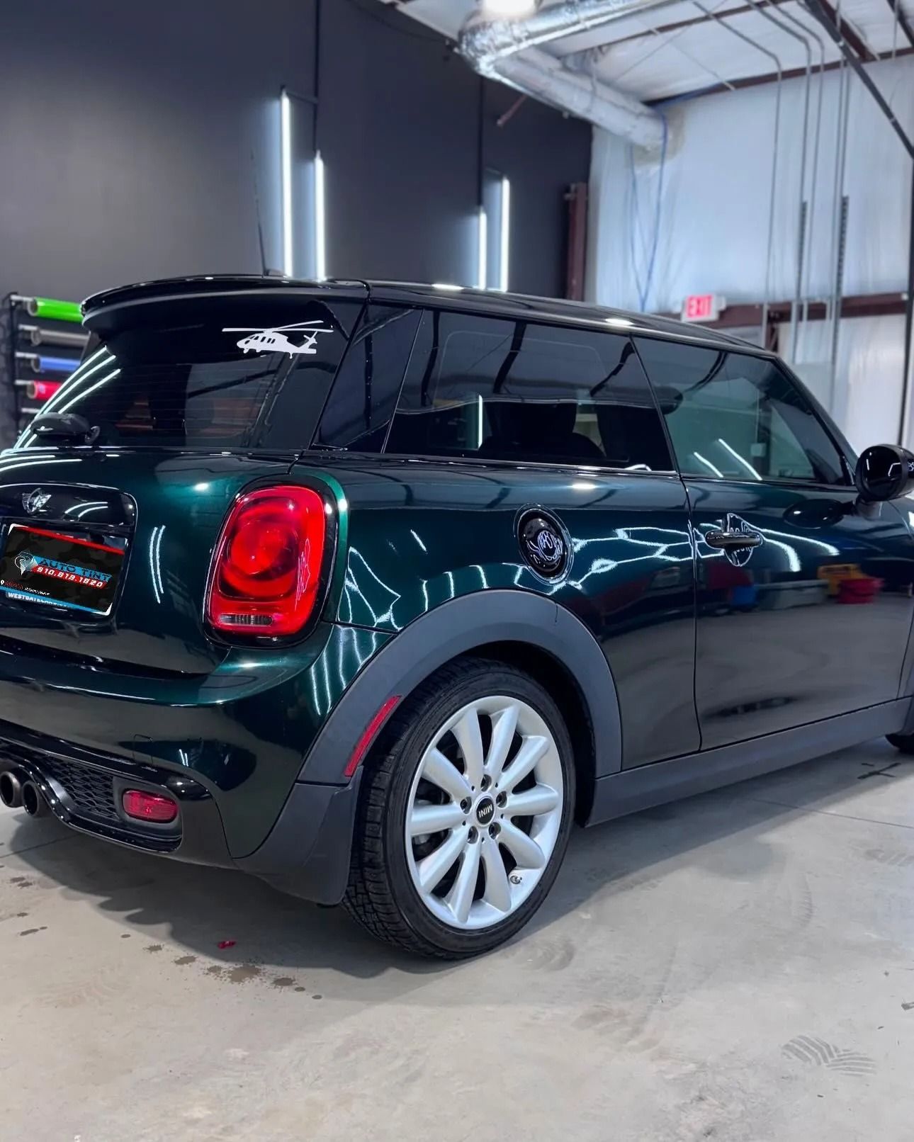 Dark green Mini Cooper with tinted windows, parked inside a garage.