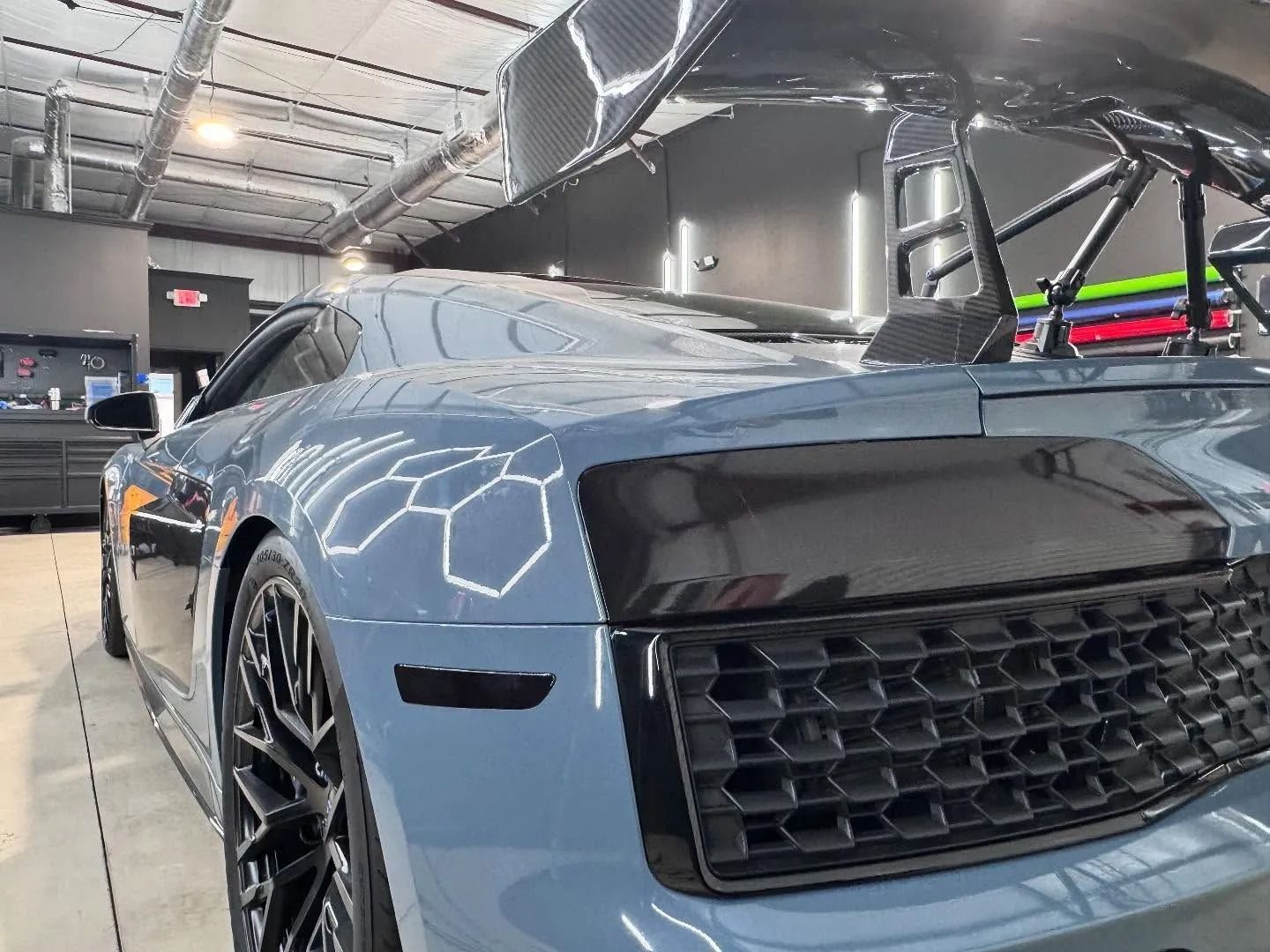 Blue Audi R8 sports car with black accents and a large carbon fiber spoiler.