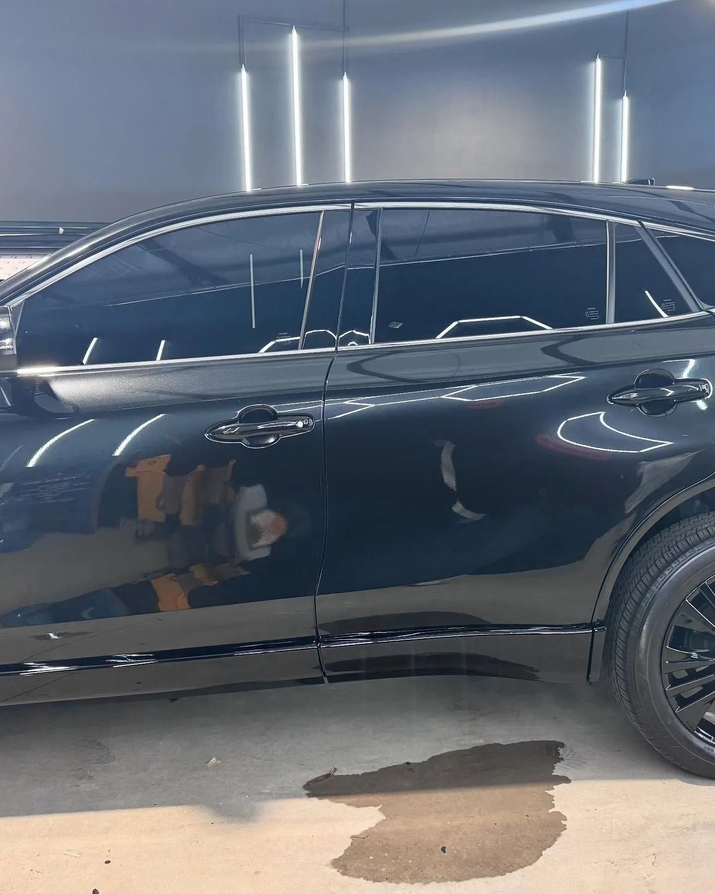 Black car with tinted windows in a well-lit space, possibly a car wash or detailing shop.
