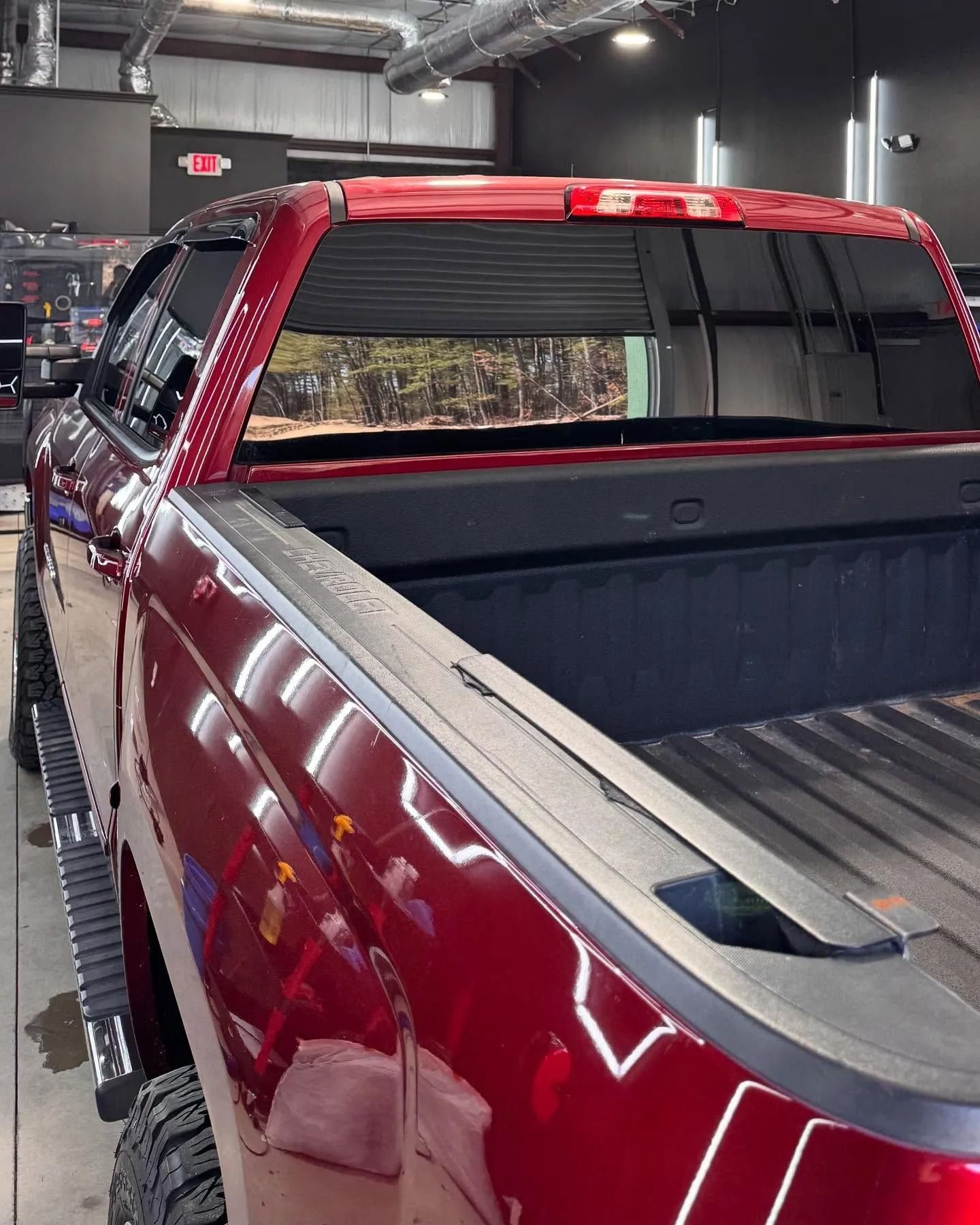 Red pickup truck bed with tonneau cover, in a garage.