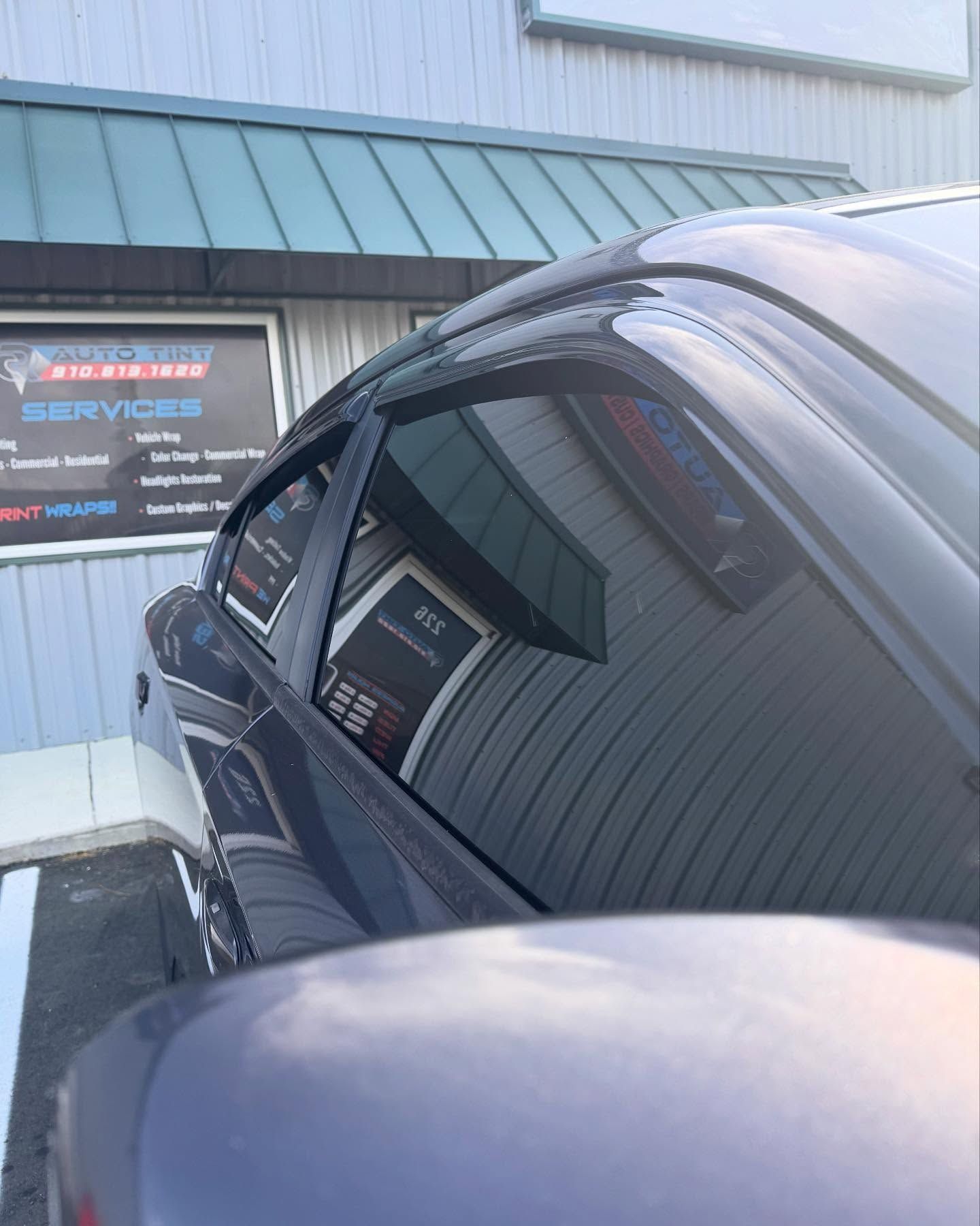 Dark car reflecting a building with signage for 