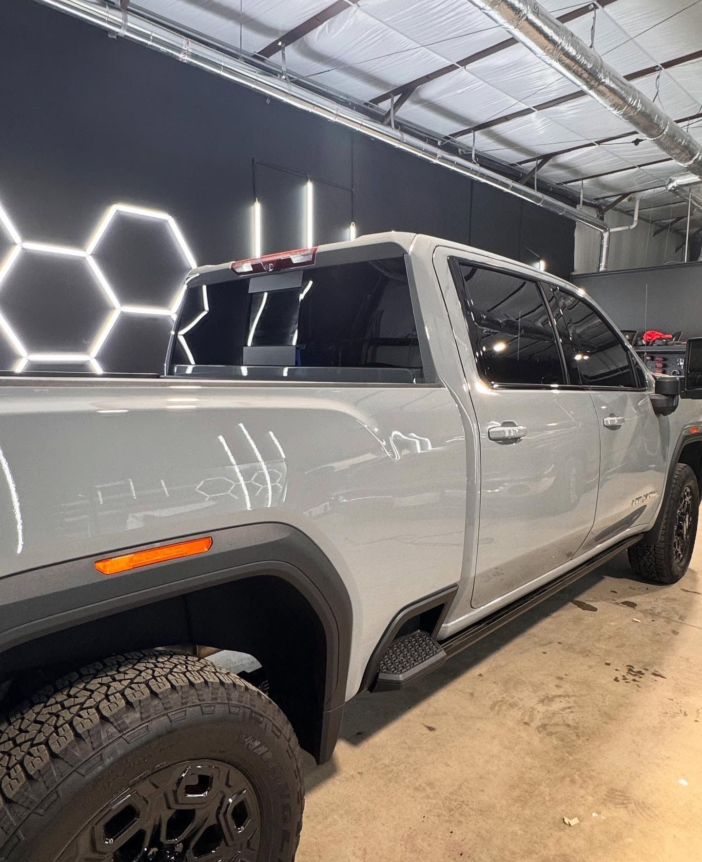 Gray pickup truck with black wheels and tinted windows in a garage.