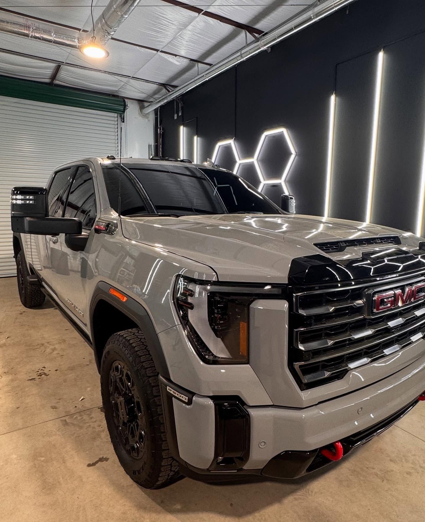 Gray GMC truck in a garage with black trim and honeycomb lights.