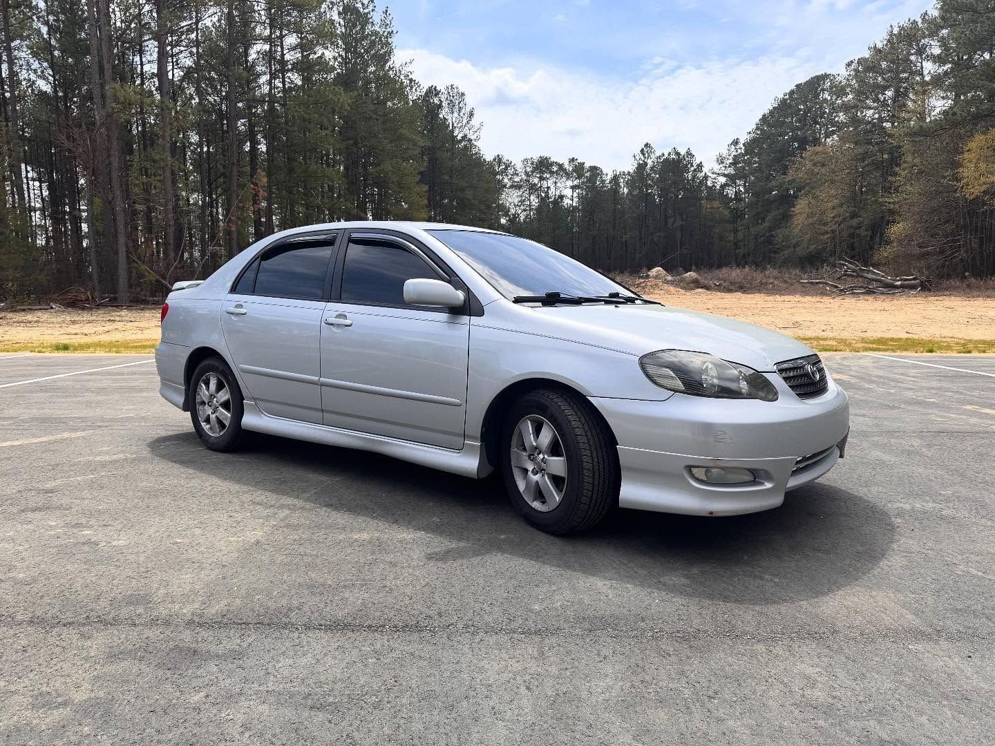 Silver Toyota Corolla sedan parked on asphalt.