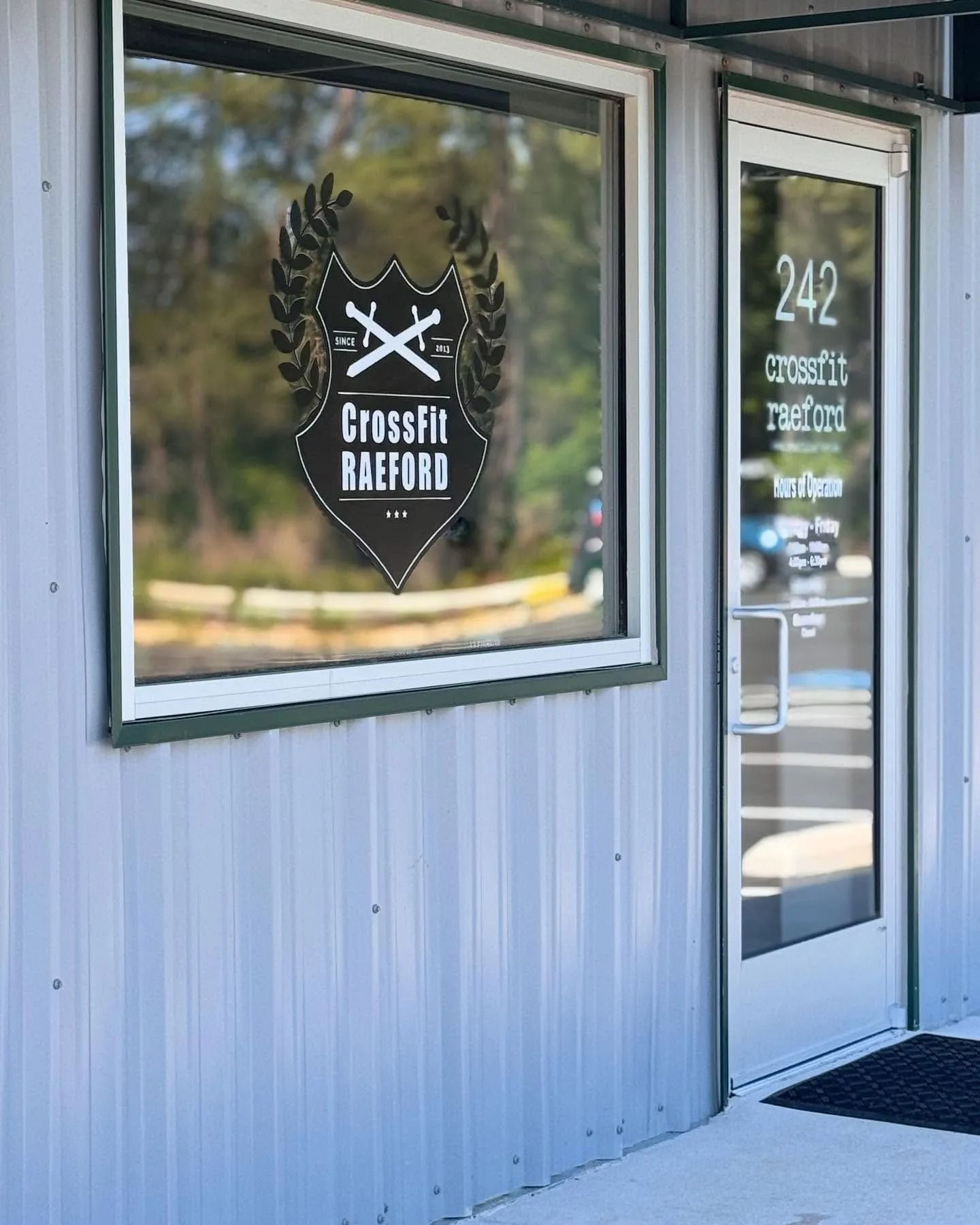 Exterior of CrossFit Raeford gym with logo on window and address 242 on door.