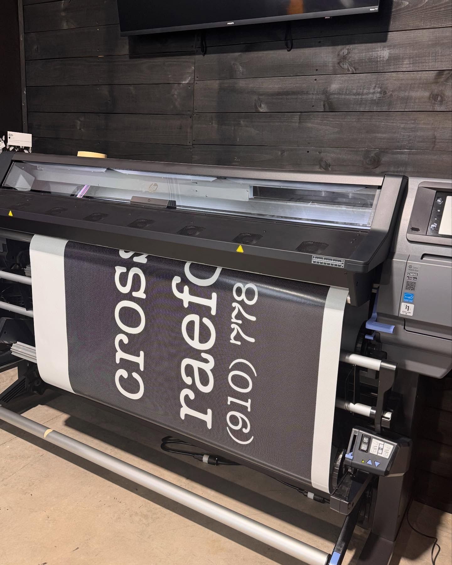 Large format printer printing a black and white banner. The banner reads 