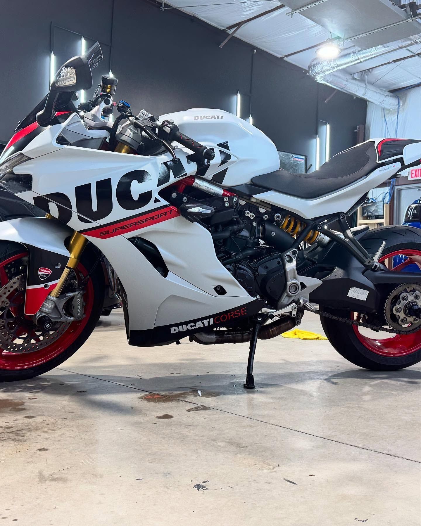 White Ducati motorcycle with black and red accents, parked indoors.
