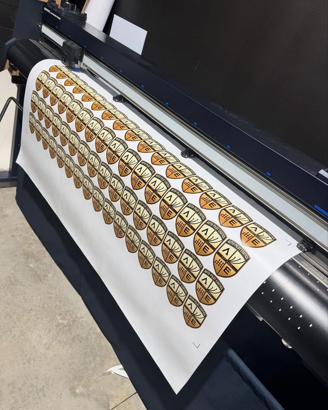 Large-format printer printing a sheet of stickers with a brown and tan design.