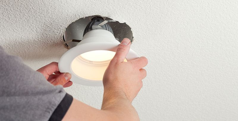 A person is installing a light fixture in a ceiling.