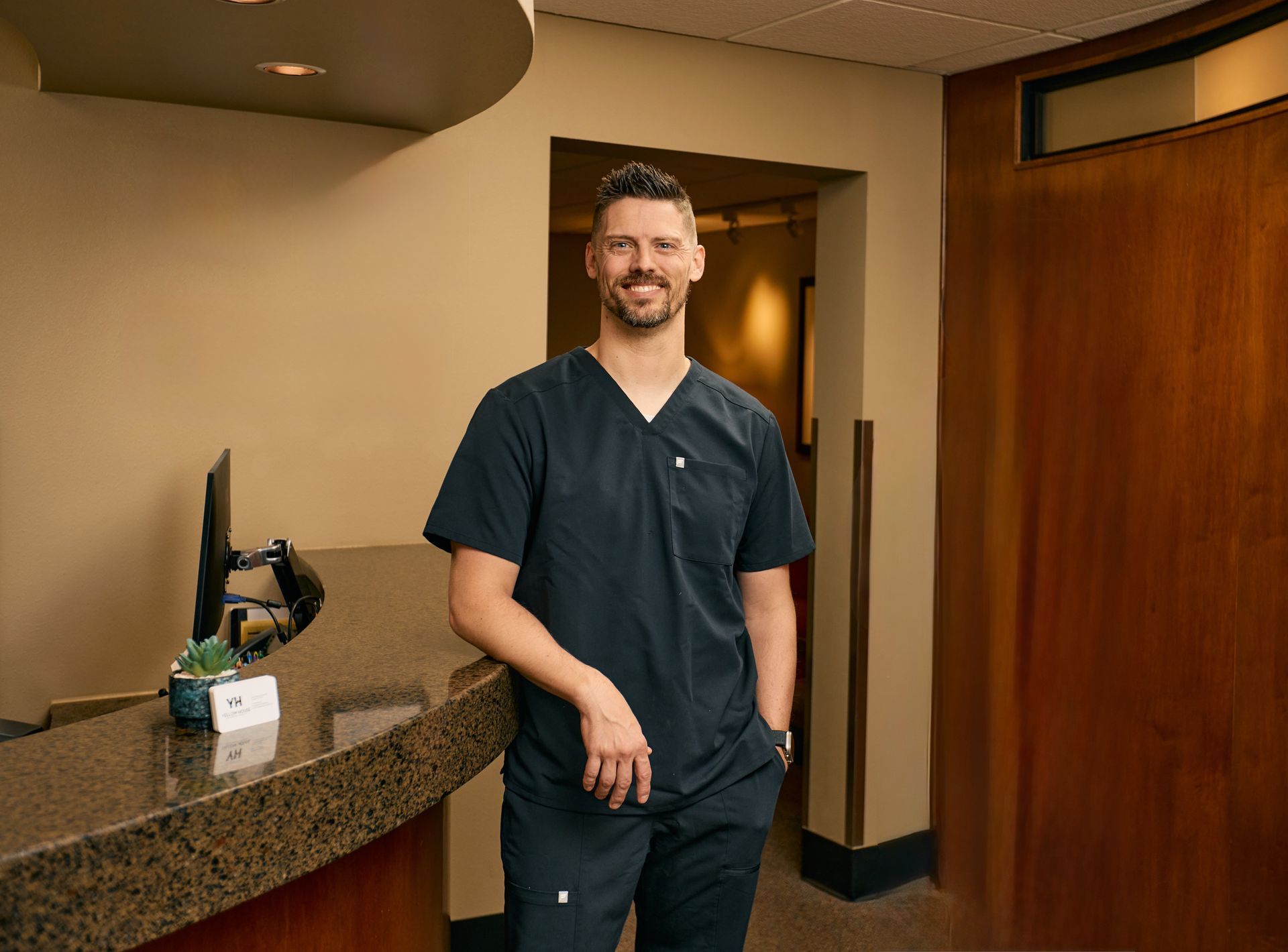 Dentist examining a patient's teeth with a mirror. Patient's mouth open, white teeth visible.